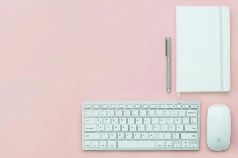 silver apple keyboard and magic mouse on a pink surface